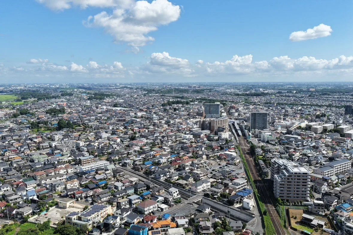 駅と線路沿いに広がる住宅街を上空から見た風景